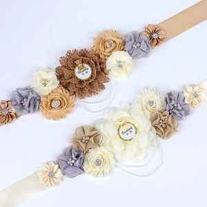 Detailed view of floral maternity sash set with Mommy To Be badges and pearls