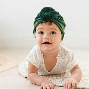Detail of baby donut turban hat in dark green velvet fabric for toddlers