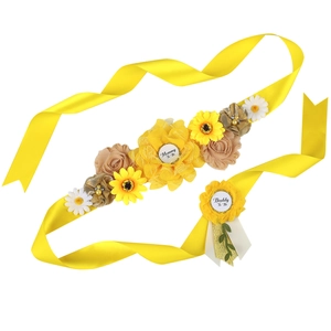 Close-up of yellow floral Mommy To Be sash and Daddy To Be badge set for baby showers