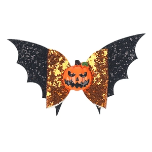 Detail of Halloween bow hair clip featuring orange pumpkin and black glitter bat wings