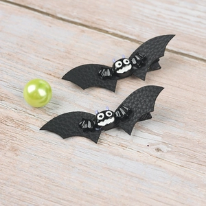 Close-up of Halloween bat hair clips featuring black faux leather wings and cartoon bat