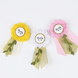 Three colorful Daddy To Be flower corsages in yellow, white, and pink for baby showers
