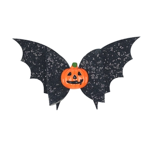 Detail view of glittery black bat wing hair clip with a classic pumpkin center