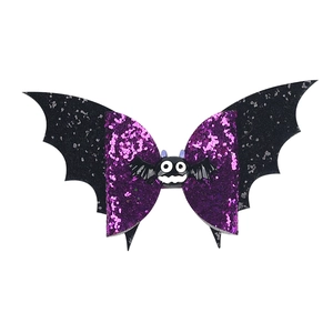 Detailed view of Halloween purple sequin bow hair clip with black bat wings and cartoon charm