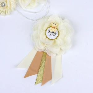 Close-up of Daddy To Be corsage with beige flowers, lace, and cute bear ornament detail