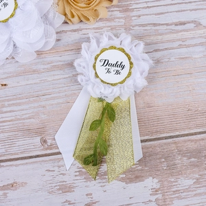 Macro detail of Daddy To Be corsage with white tulle and gold ribbons on wood