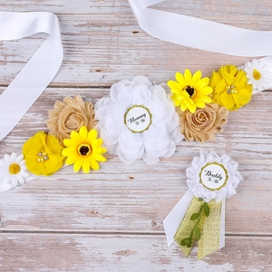 Close-up of sunflower maternity sash and Mommy To Be floral corsage on wood background