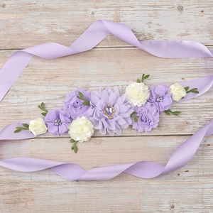 Detailed view of handmade maternity sash with purple fabric flowers and pearl accents