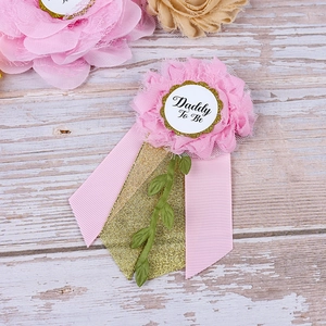 Close-up of pink and gold Daddy To Be baby shower badge with lace and ribbon detail