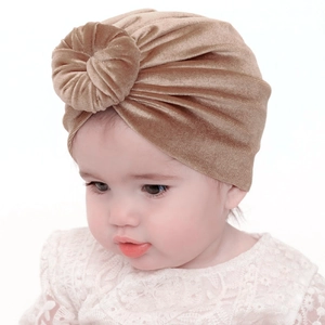 Detail of baby velvet turban hat in champagne gold with a decorative donut knot design