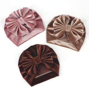 Macro view of velvet baby turbans featuring large bows in pink, beige and brown tones