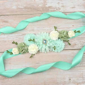 Detail of mint green maternity sash with handmade chiffon flowers and rhinestone center