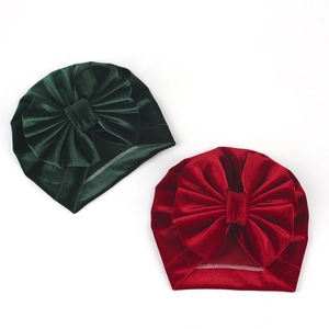 Detail view of velvet baby turban hats with large leopard print bows in green and burgundy