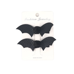 Macro detail of black leather bat wing hair clips with glitter ball on white display card