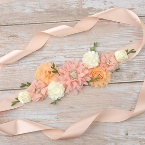 Detail of pink and white fabric flowers with rhinestones on a silk ribbon maternity sash