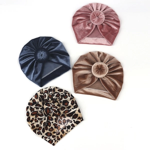 Flat lay of velvet baby turban hats in pink, navy, brown and leopard print colors