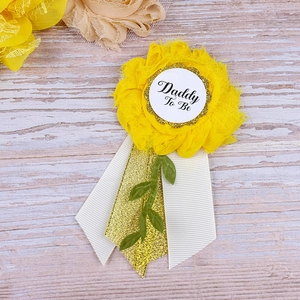 Detail of yellow flower sash badge for Dad To Be with gold glitter ribbons and text