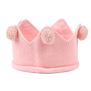 Gros plan d'un bandeau couronne en tricot rose pour bébé avec pompons doux et texture
