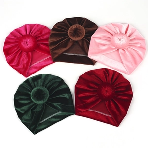 Detail view of colorful velvet baby turban hats with top knot balls in five rich shades