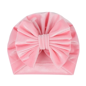 Detail of pink velvet baby turban hat featuring a large bow and soft textured fabric