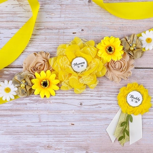 Detail of yellow sunflower maternity sash and Mommy To Be badge on wood background