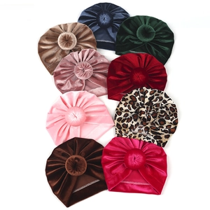 Flat lay of soft velvet baby turban hats in nine colors including leopard and solid tones