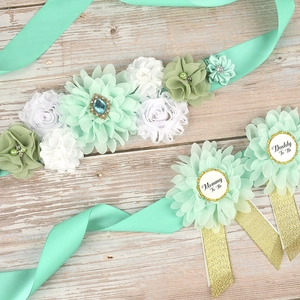 Close-up of mint green baby shower floral sash and badges for Mommy and Daddy to be