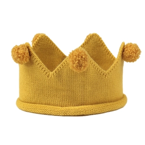 Détail du bonnet couronne en tricot jaune pour bébés avec côtes souples et pompons