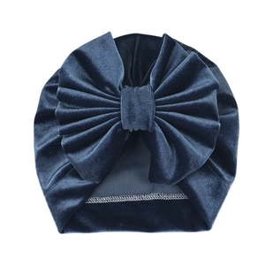 Detail of dark blue velvet baby turban hat featuring a large bow and fine overlock stitching