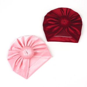 Detail of baby velvet turban hats in pink and dark red with top knot and soft pleats