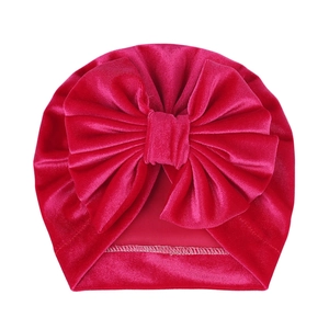 Macro detail of deep rose red velvet baby turban hat with a large bow decoration