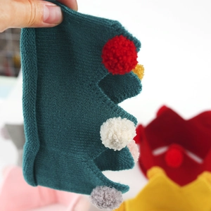 Détail d'un bonnet couronne en tricot vert avec pompons colorés pour fête de bébé