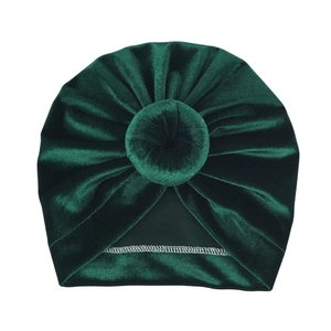 Detailed close-up of dark green velvet baby turban hat with soft donut knot decoration