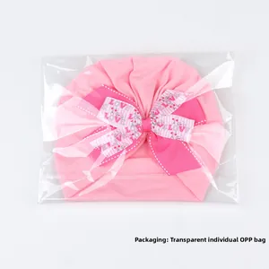 Détail du turban rose pour bébé avec double nœud dans un sac OPP individuel clair