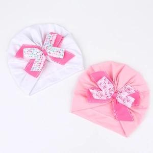Détail de turbans pour bébé avec grands nœuds cœurs en blanc et rose tendre
