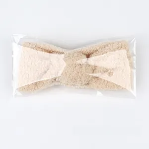 Detail eines warmen Teddy-Fleece-Stirnbands in Beige mit Schleife in der Einzelverpackung