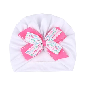 Détail du bonnet turban pour bébé avec un double nœud orné de motifs de cœurs colorés