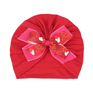 Vue détaillée du bonnet turban rouge pour bébé avec un nœud imprimé cœur et tissu en coton doux