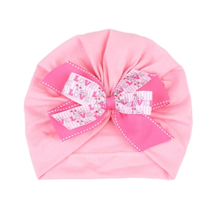 Détail du bonnet turban rose pour bébé avec un grand nœud décoré de motifs Love et vélo