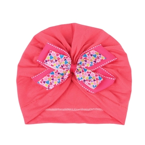 Détail du bonnet turban bébé montrant le nœud à cœurs colorés et le tissu en coton doux