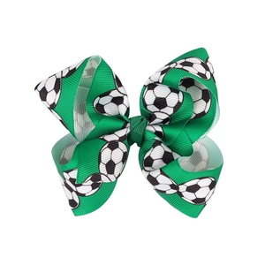 Dettaglio del fiocco per capelli in gros-grain verde con motivi realistici di palloni da calcio