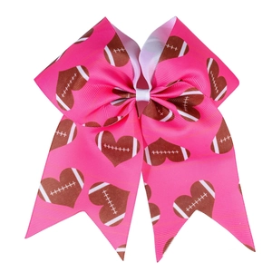 Detail of pink grosgrain ribbon hair bow with brown American football heart pattern
