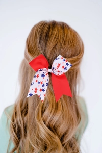 Detail of a red white and blue star bow hair tie on a child's golden brown hair