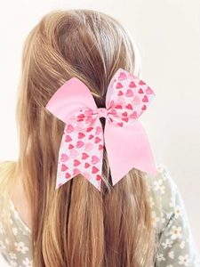 Vue de dos d'une fille portant un nœud papillon rose à motif cœurs sur cheveux blonds