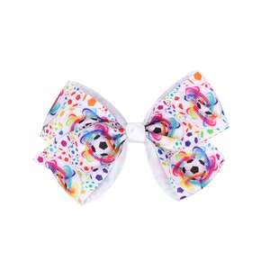Detailed close-up of a white grosgrain ribbon hair bow with soccer ball and rainbow prints