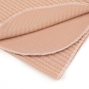 Détail macro de maille gaufrée de couleur chameau avec coutures surjetées blanches