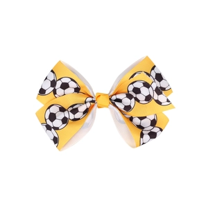 Close-up of yellow grosgrain hair bow featuring classic soccer ball patterns for kids