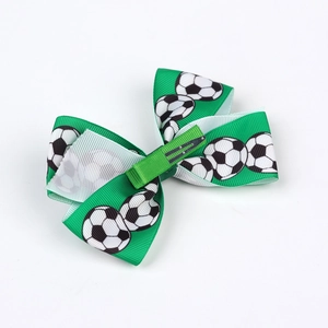 Close-up of a green football print bow hair clip with silver metal alligator clamp