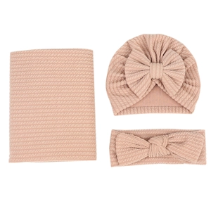 Détail d'un ensemble de lange en tricot gaufré rose avec bonnet et bandeau assortis