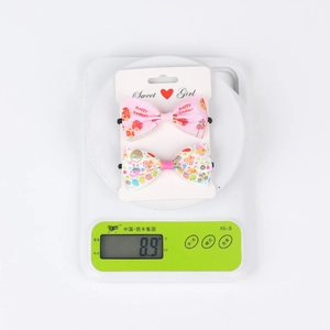 Detail showing two Easter hair clips with pink stripes and floral patterns on a scale